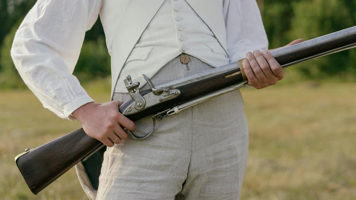 Close-up of a reenactor in historical soldier uniform with musket, outdoors.