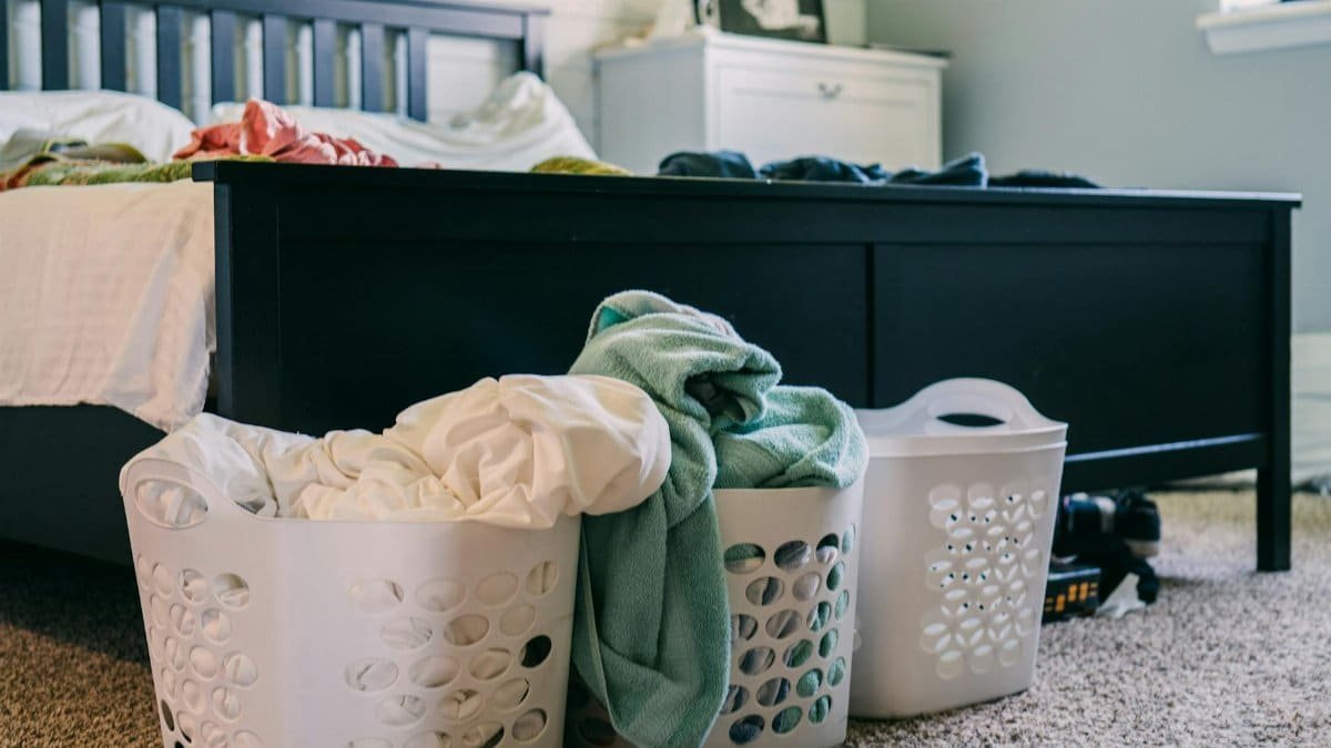 A cozy bedroom scene featuring laundry baskets filled with clothing, placed on a carpeted floor.