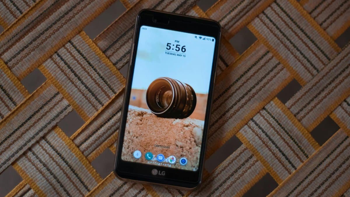 An LG smartphone displaying time on a textured table surface.