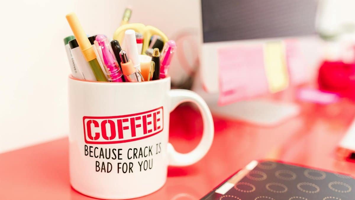 Humorous coffee mug filled with pens on a vibrant office desk, creating a quirky workspace vibe.