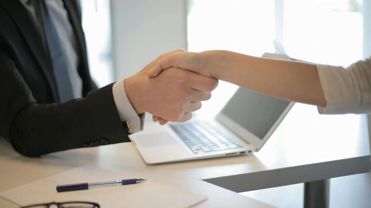 Close-up of a professional handshake over a laptop during a business meeting in an office.