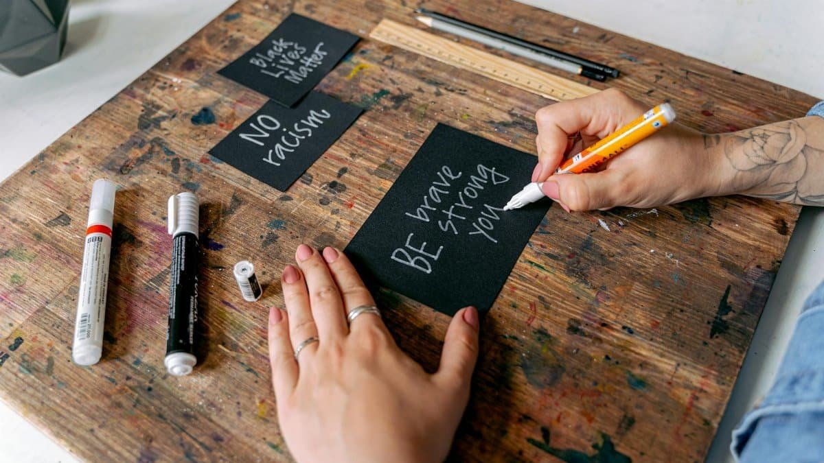 Close-up of hands writing motivational messages on cards against racism.