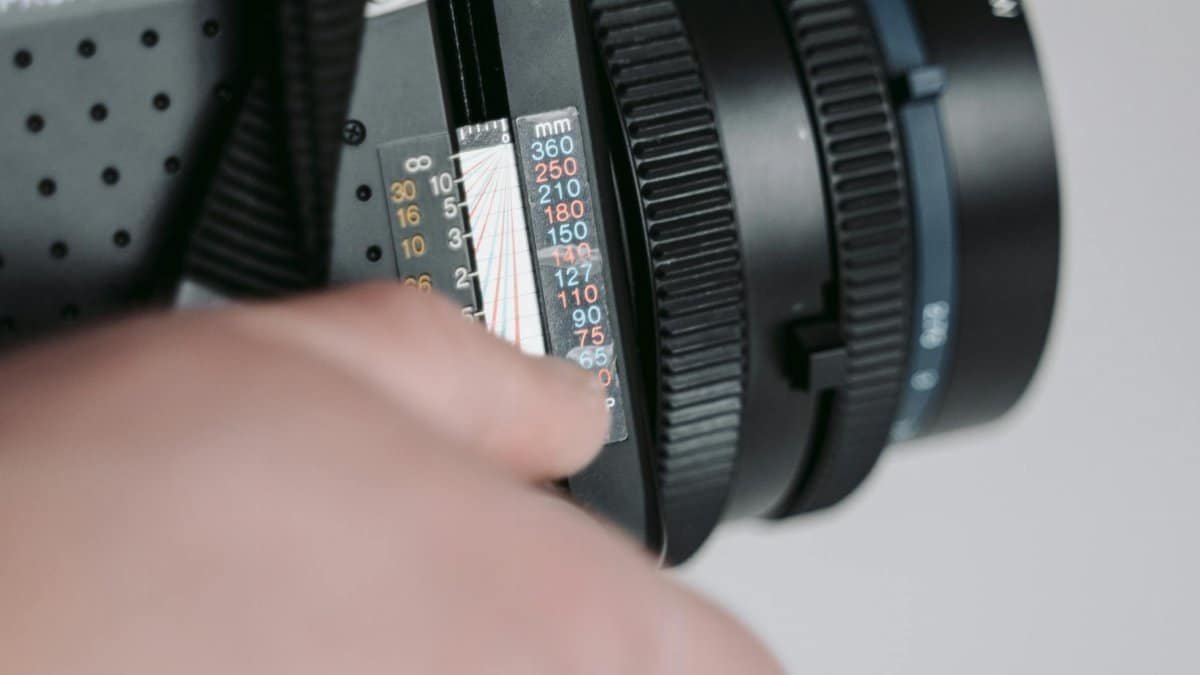 Macro shot of hand adjusting settings on a professional camera lens.