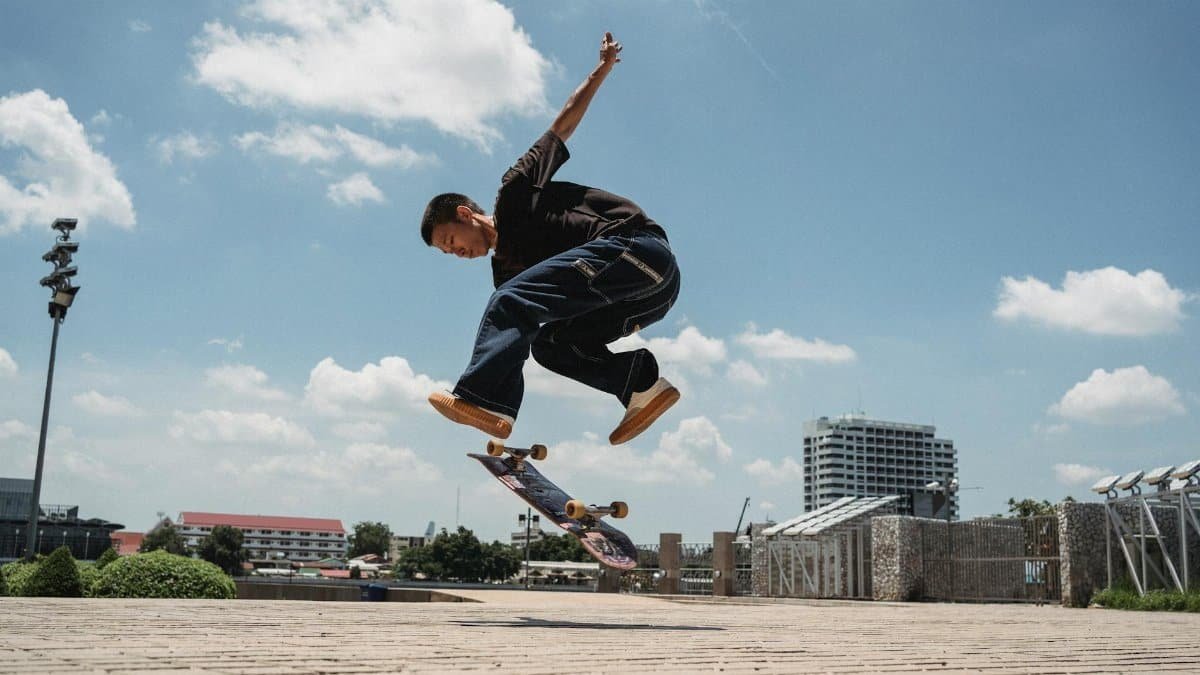 A skilled skater executing an impressive trick in an outdoor urban environment under a clear blue sky.