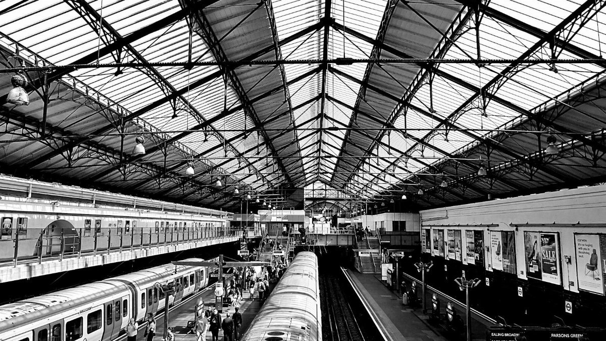 Black and white view of a bustling train station with people and trains.