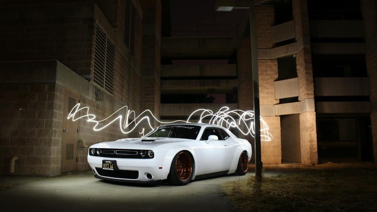 White luxury sports car parked with dynamic light trails at night against a building backdrop.