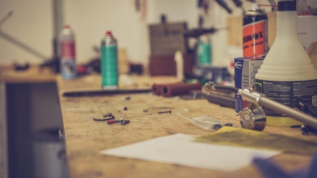 A cluttered workbench in a workshop with various tools and materials for maintenance.