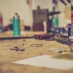 A cluttered workbench in a workshop with various tools and materials for maintenance.