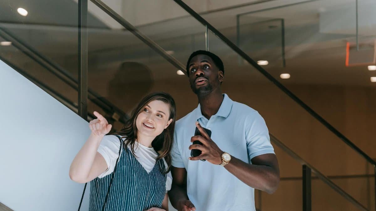 Interracial couple pointing and exploring indoors, capturing a moment of interest.