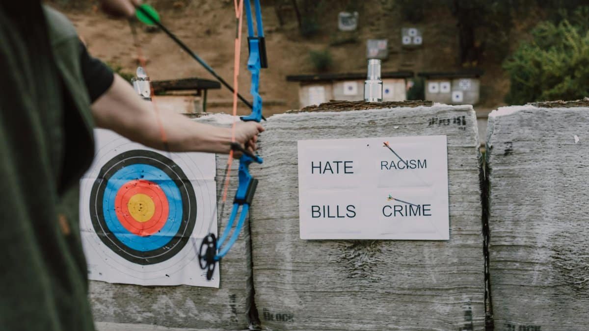 An archer aims at targets with words representing challenges outdoors, symbolizing overcoming obstacles.