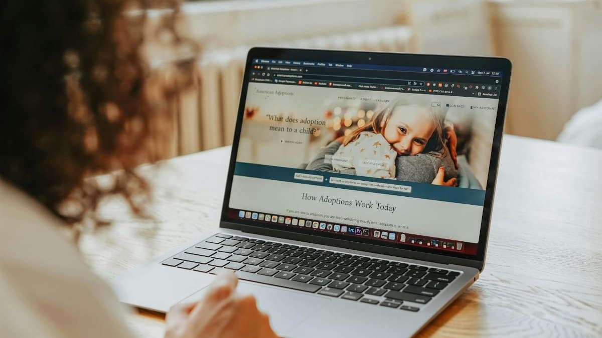 A woman researching adoption information on a laptop indoors.