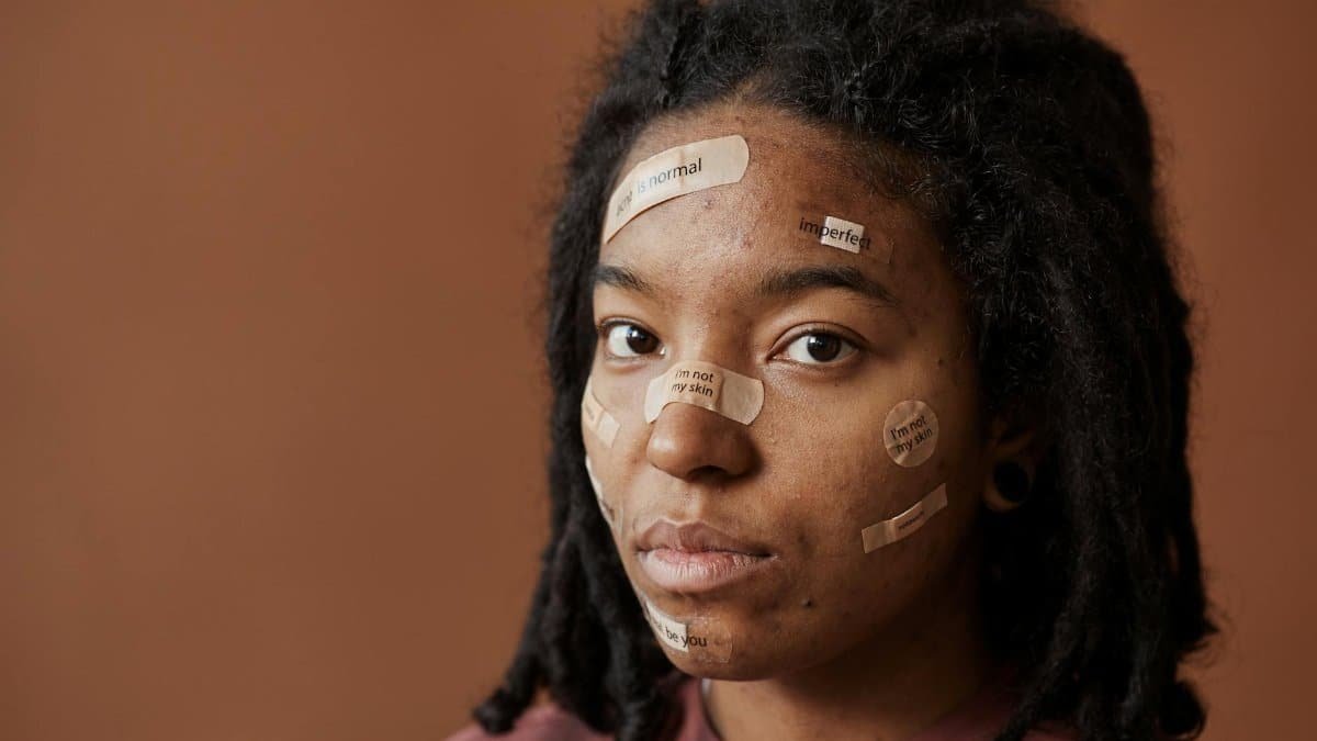 Close-up portrait of a woman with affirming messages on bandages, promoting self-acceptance.
