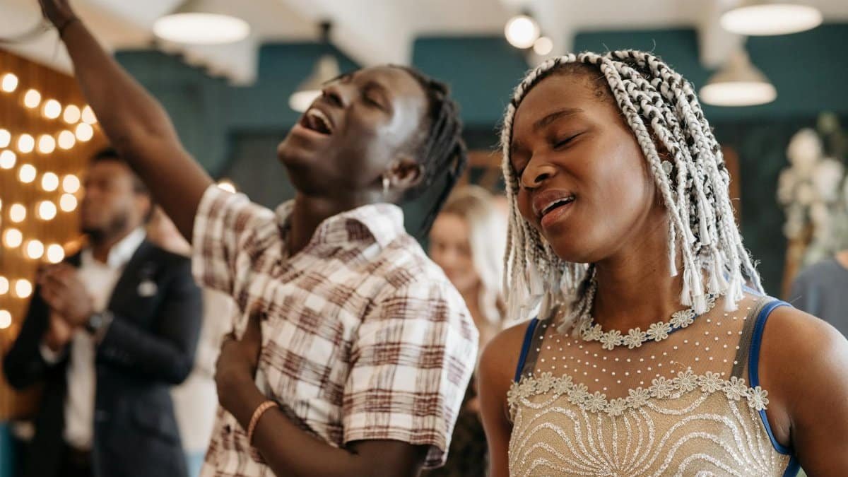 Man and woman joyfully singing in a lively church service, embodying spirituality.