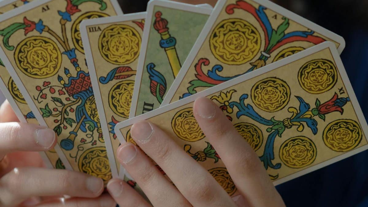 A detailed view of hands holding vibrant Tarot cards, capturing mystical themes.