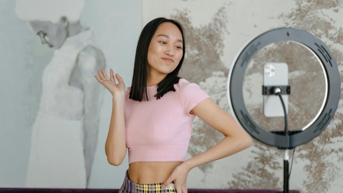 A young woman recording a dance video for social media with her smartphone indoors.