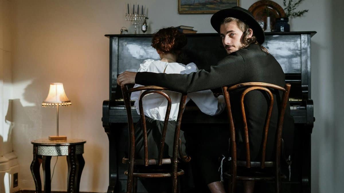 A young orthodox couple sitting at piano, creating music together in a cozy home setting.