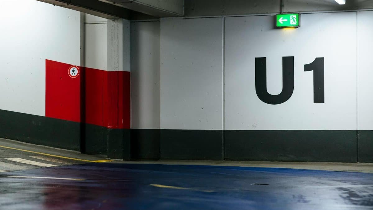 View of an empty indoor parking garage with U1 signage and exit sign.