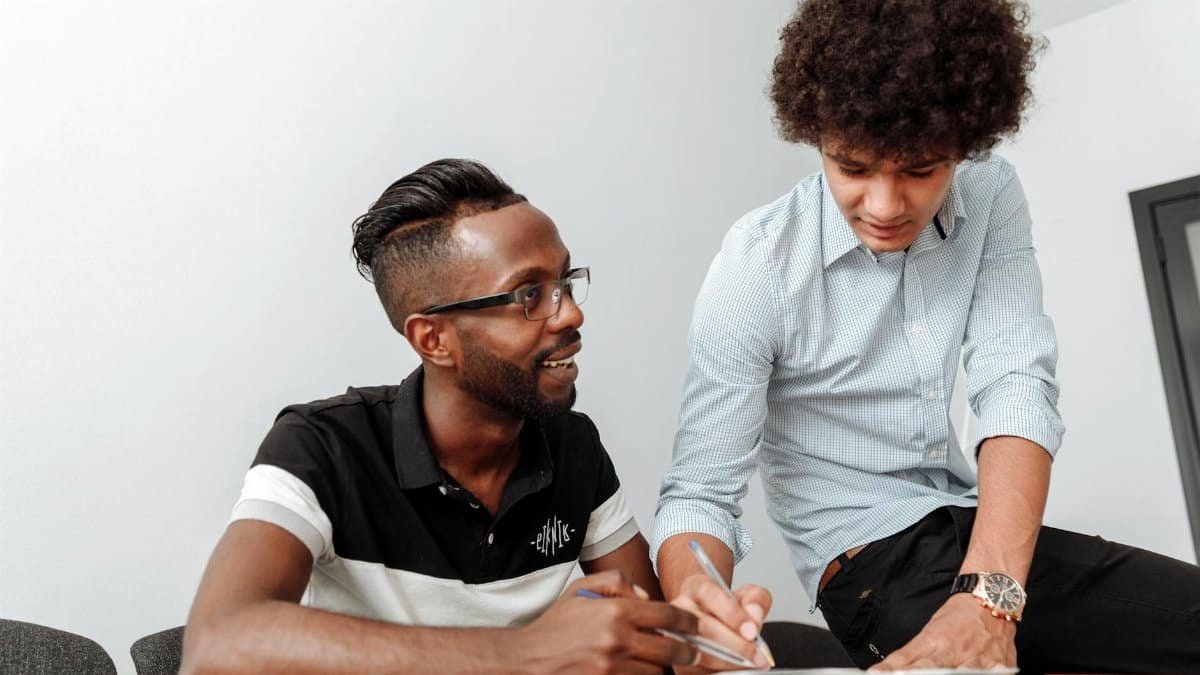 Two coworkers collaborating at a desk, emphasizing teamwork and idea sharing.