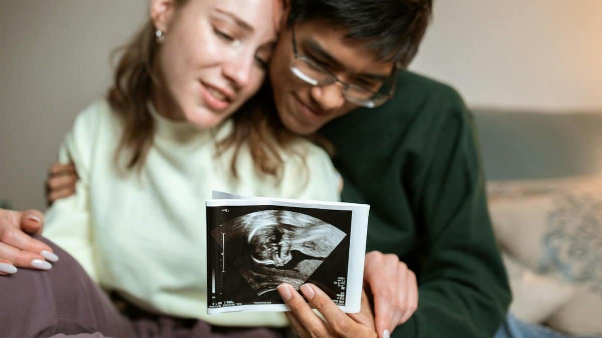 A happy couple embracing while looking at an ultrasound image of their future baby.