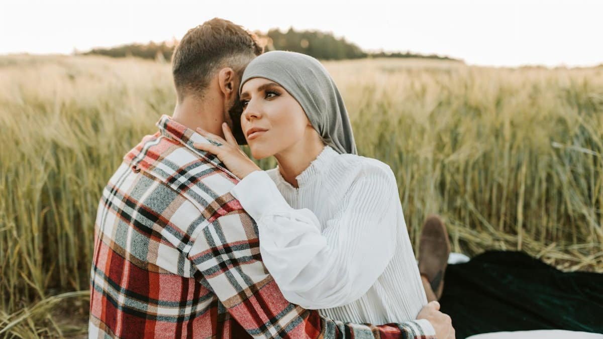 Couple embracing in a serene field during a summer day, conveying love and connection.