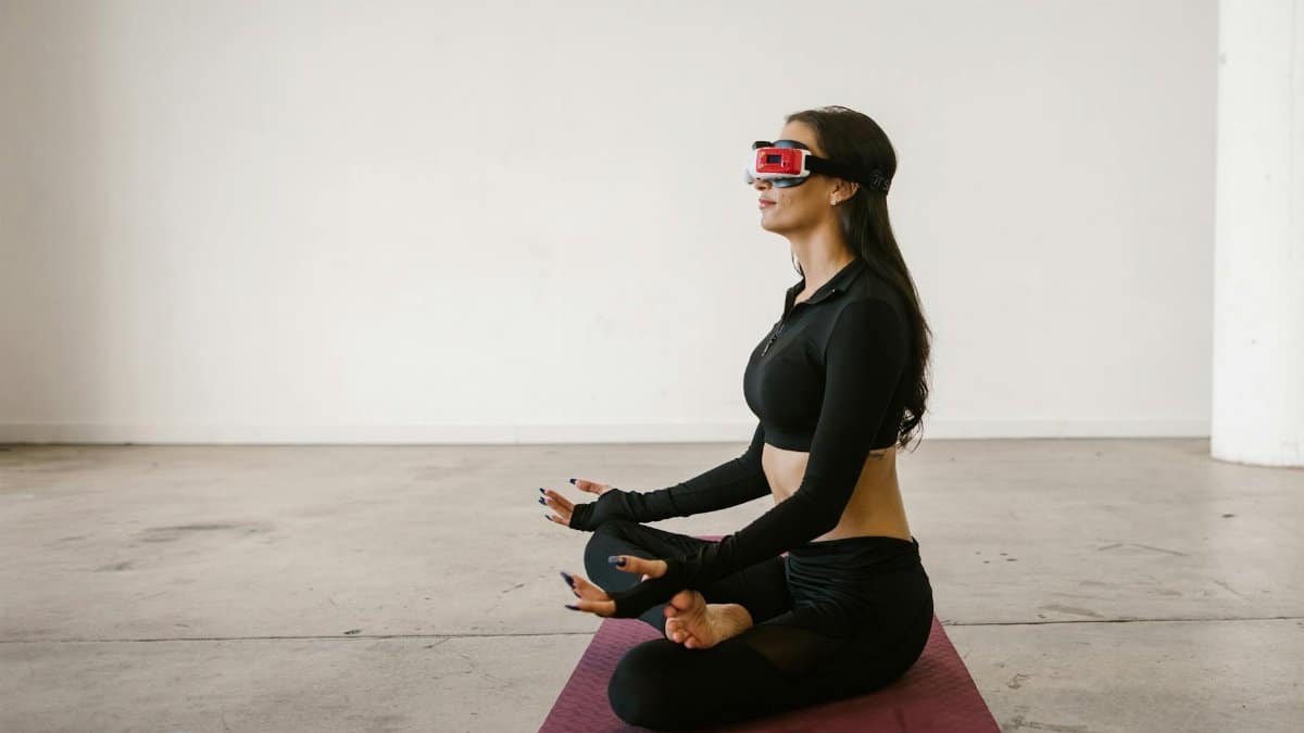 A woman practicing yoga indoors with a VR headset on, merging technology and mindfulness.