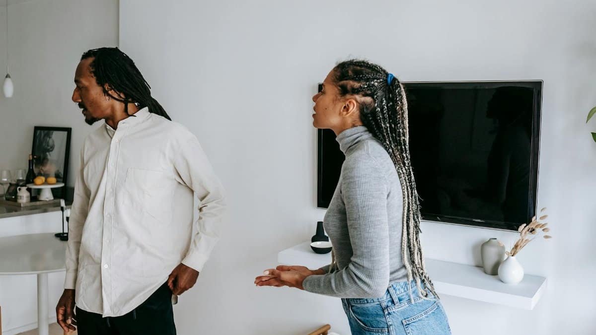 Emotional black couple standing in cozy apartment and having conflict while spending time together