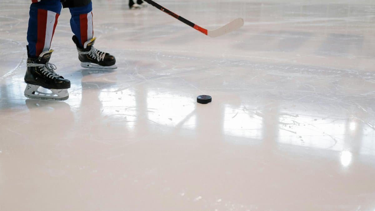 Dynamic shot of a hockey player maneuvering with stick and puck on ice rink.