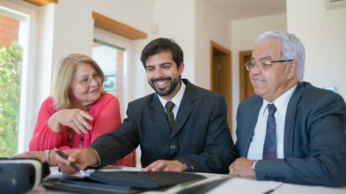 Professional realtor discussing real estate deal with senior couple in bright office setting.