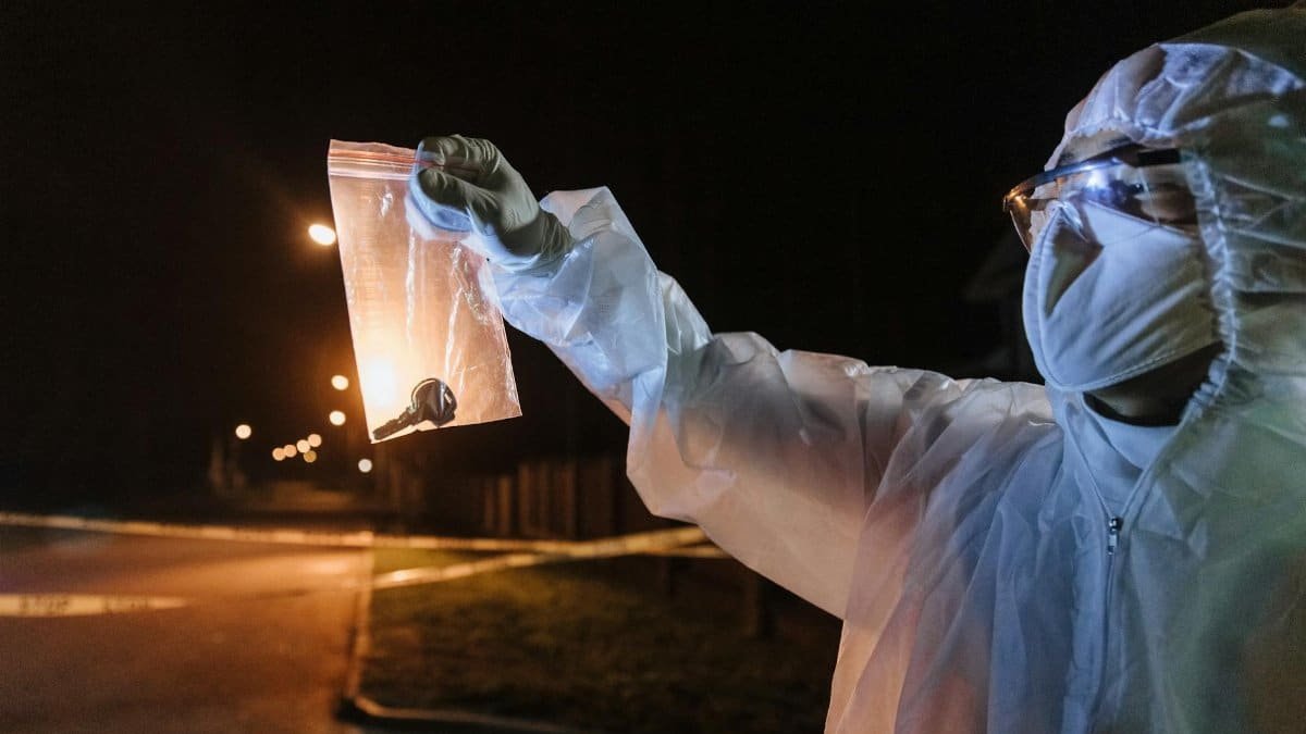 Crime scene investigator examines evidence in a nighttime urban setting.