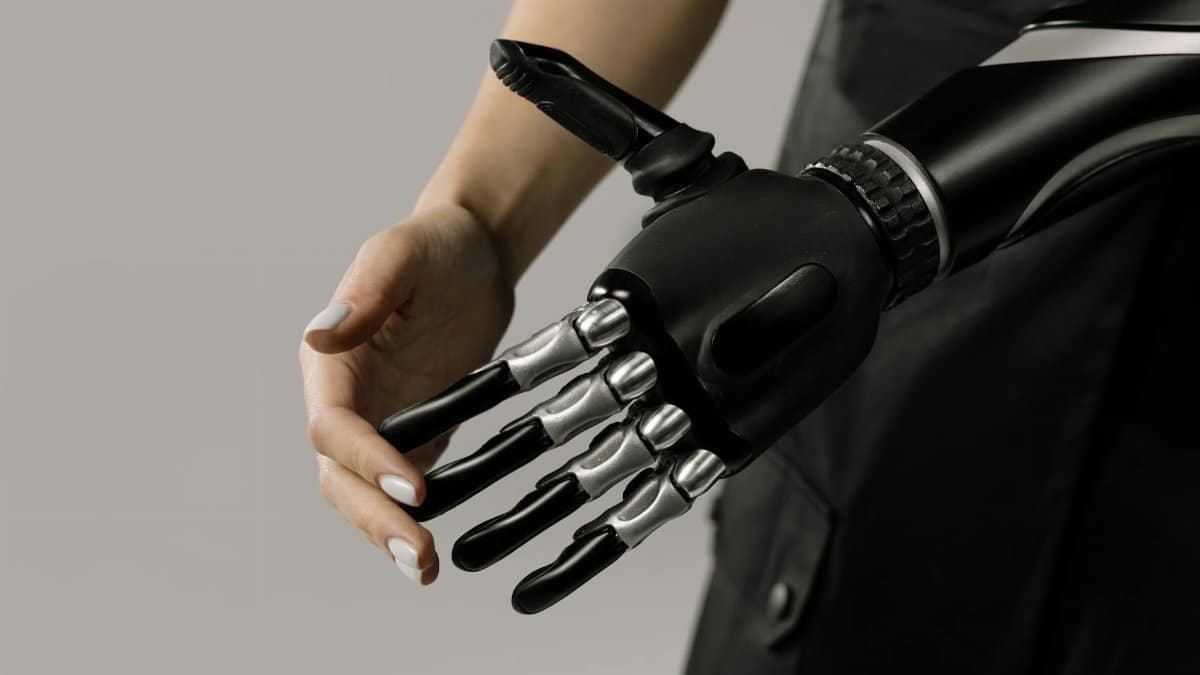 A futuristic black and chrome prosthetic arm being examined indoors, symbolizing technology integration.