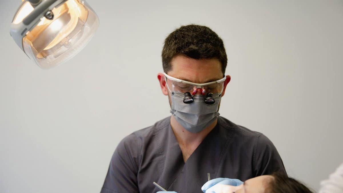 A dentist uses professional tools to treat a patient in a well-lit dental office.