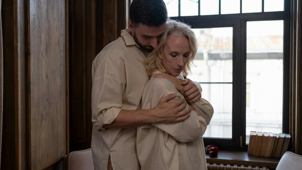 Intimate moment of a couple embracing by a window, blending affection and warmth.