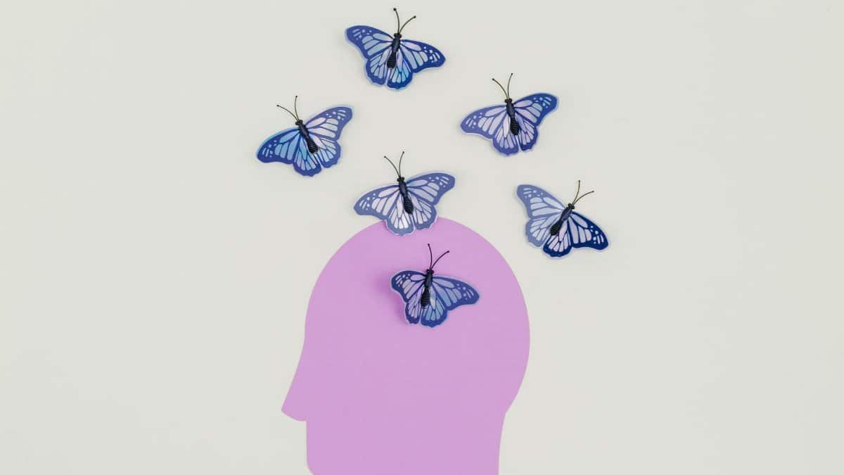 Purple silhouette with blue butterflies illustrating creative thoughts.