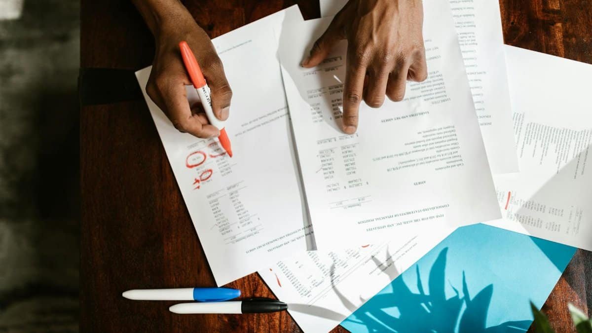 Overhead view of hands highlighting financial documents on a desk.