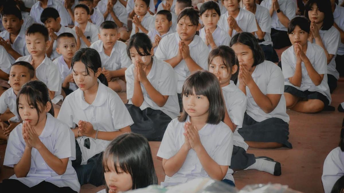 Students in uniform meditating at a school assembly, focused and serene.