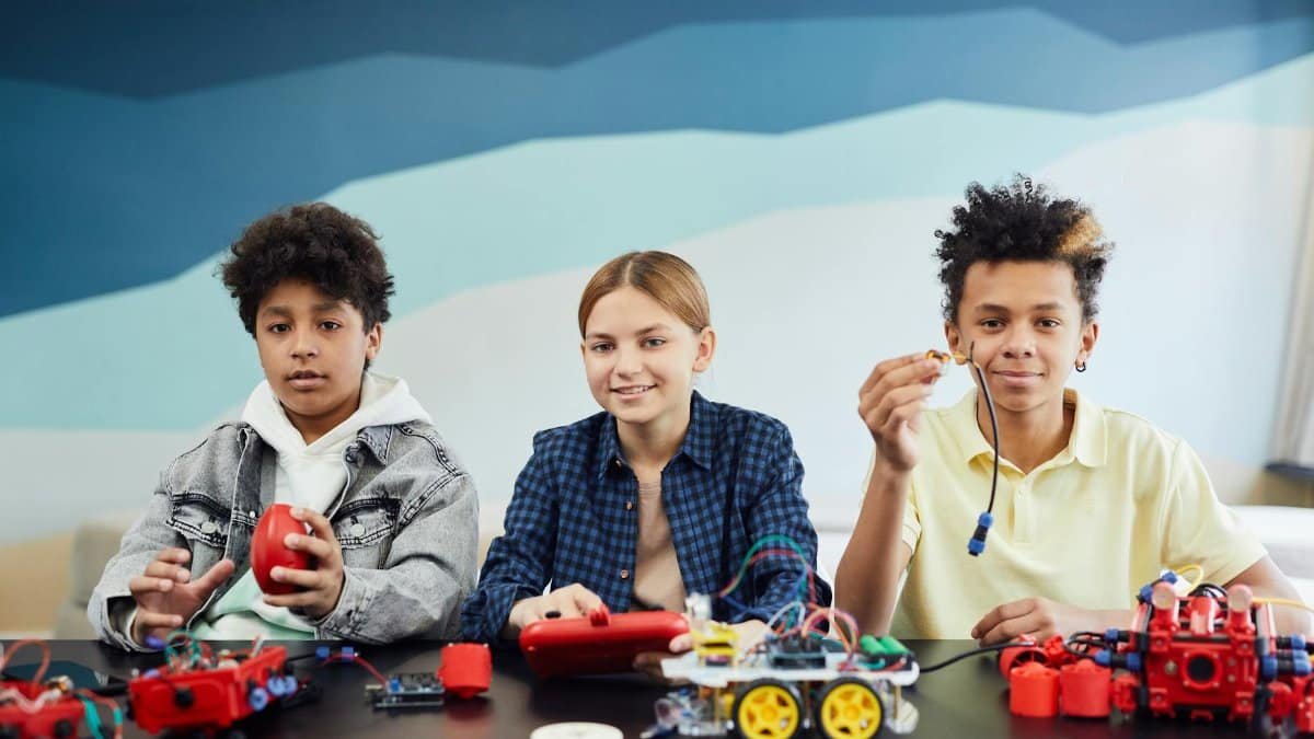 Three children working together on a robotics project indoors. Educational teamwork activity.