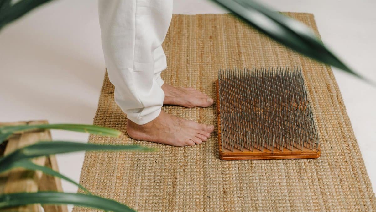 Barefoot acupressure practice on nail board to promote relaxation and meditation indoors.