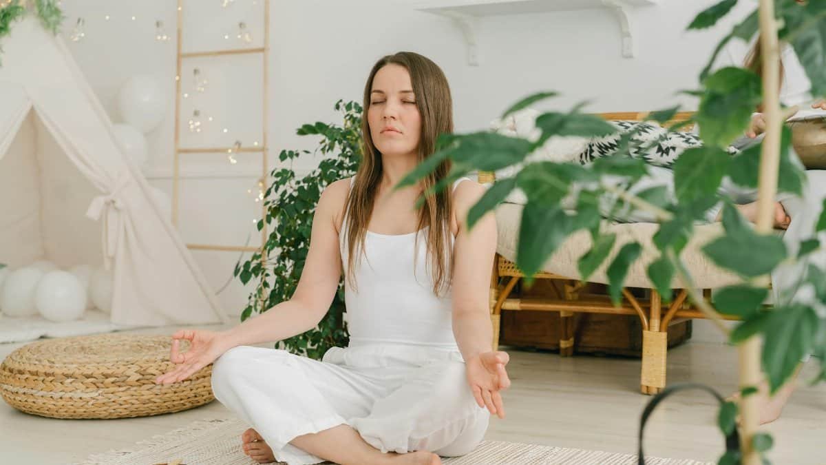 Peaceful meditation scene with a woman practicing mindfulness in a cozy, plant-filled indoor space.