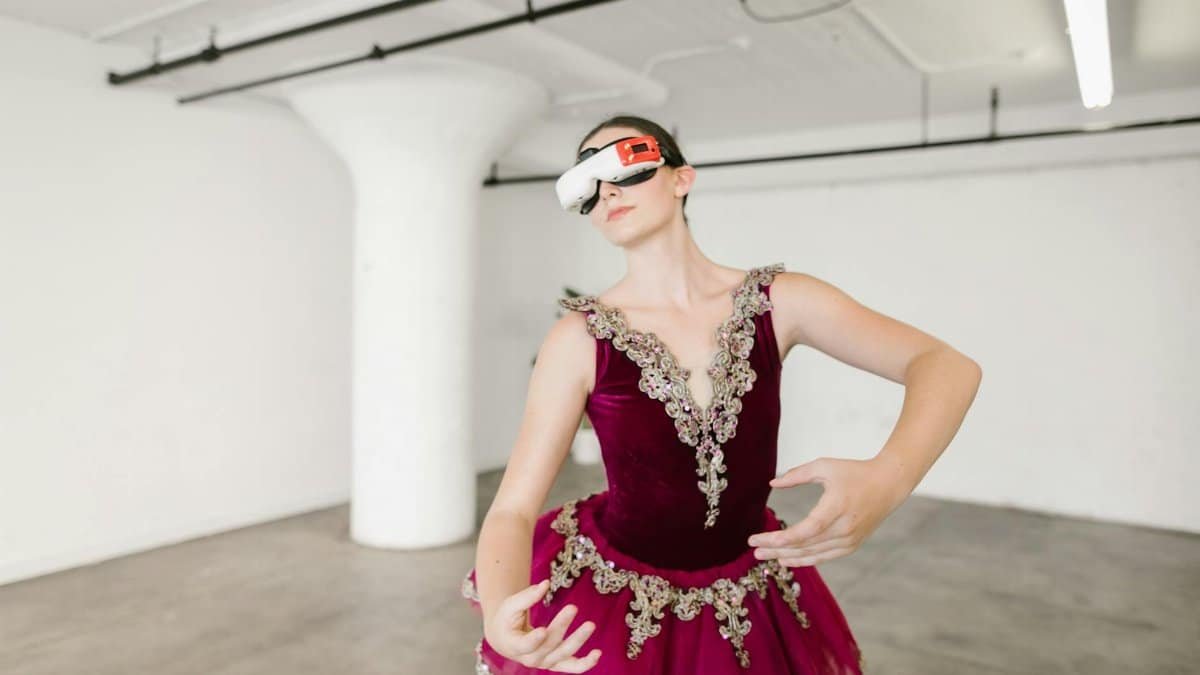 Elegant ballet dancer wearing VR headset inside a modern studio.