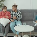 A family therapy session with parents discussing things while a child is absorbed in her smartphone.