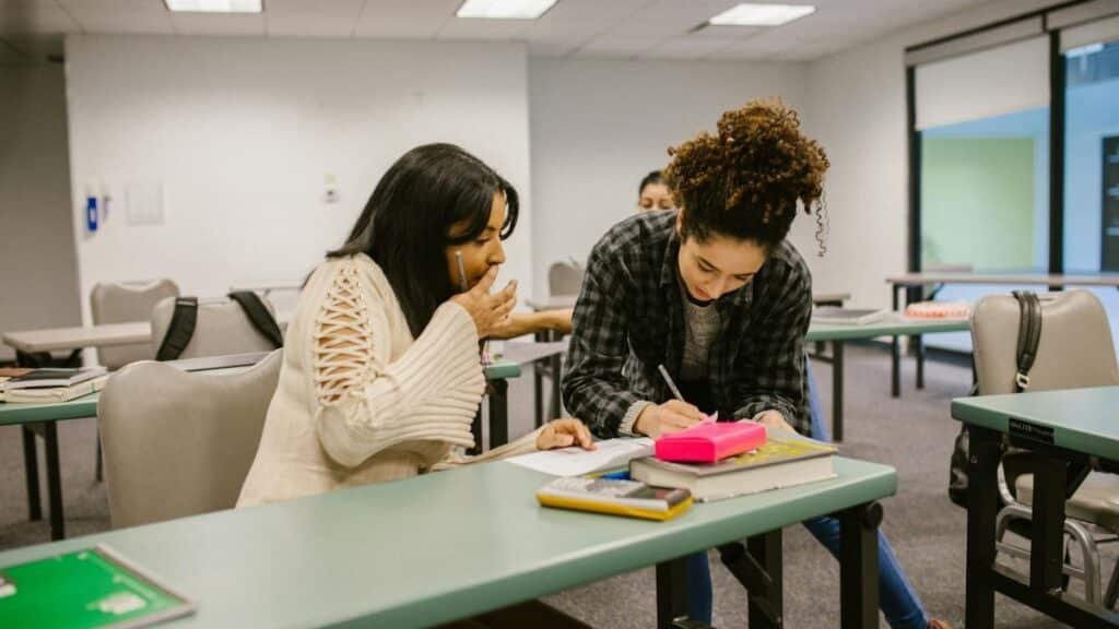 Two female students collaborate in a classroom setting, focusing on their studies.