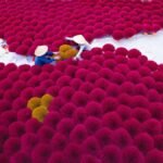 Aerial view of colorful incense sticks being dried outdoors with two workers in traditional hats.