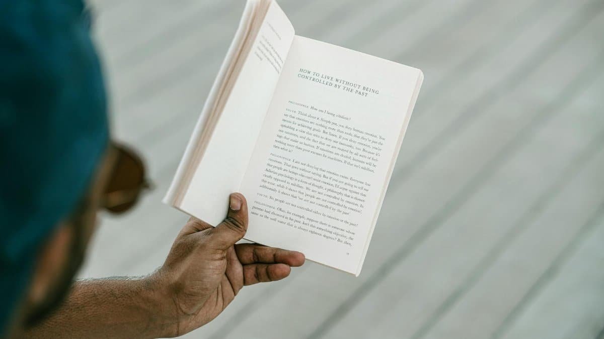 A person engrossed in reading an inspirational book outdoors on a sunny day.