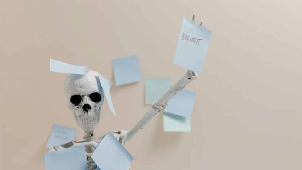 Humorous depiction of burnout with a skeleton holding sticky notes, representing overwork.