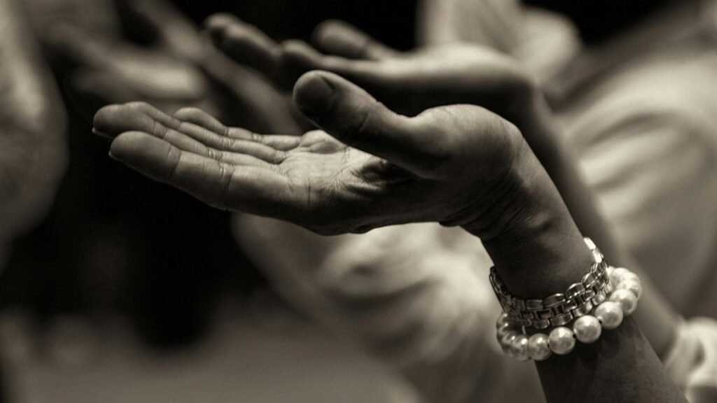 Close-up of expressive hands in prayer wearing a bracelet, conveying faith and devotion.