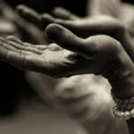 Close-up of expressive hands in prayer wearing a bracelet, conveying faith and devotion.