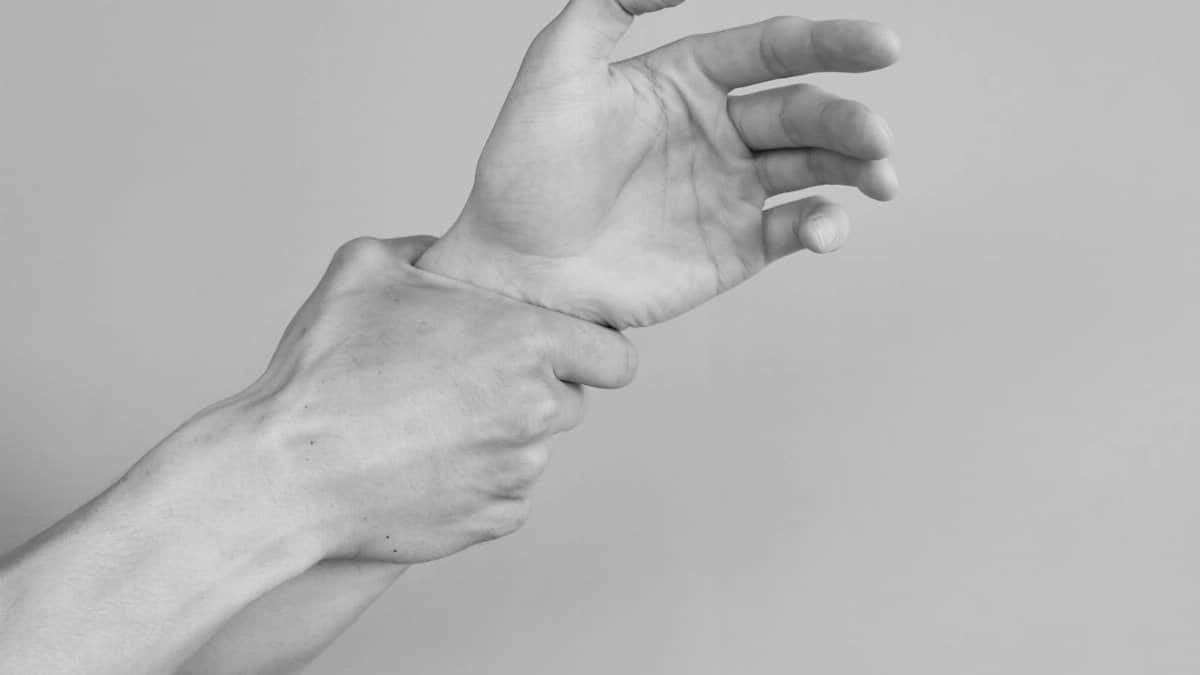 Grayscale image of hands gripping a wrist, symbolizing tension or support.