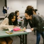 Two female students working together during a study session in a college classroom.