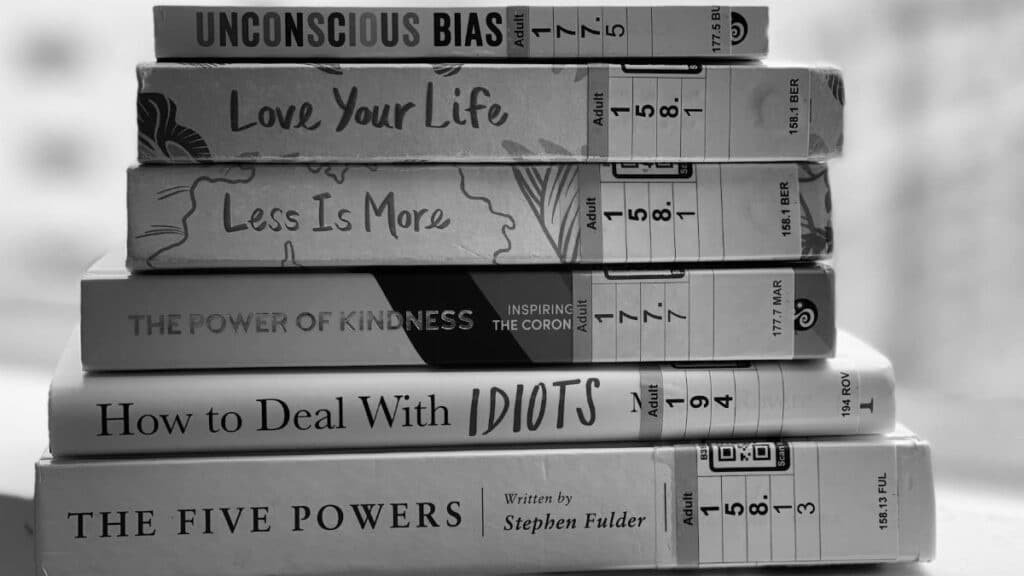 Black and white stack of self-help and inspirational books on a table.