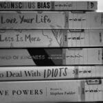 Black and white stack of self-help and inspirational books on a table.